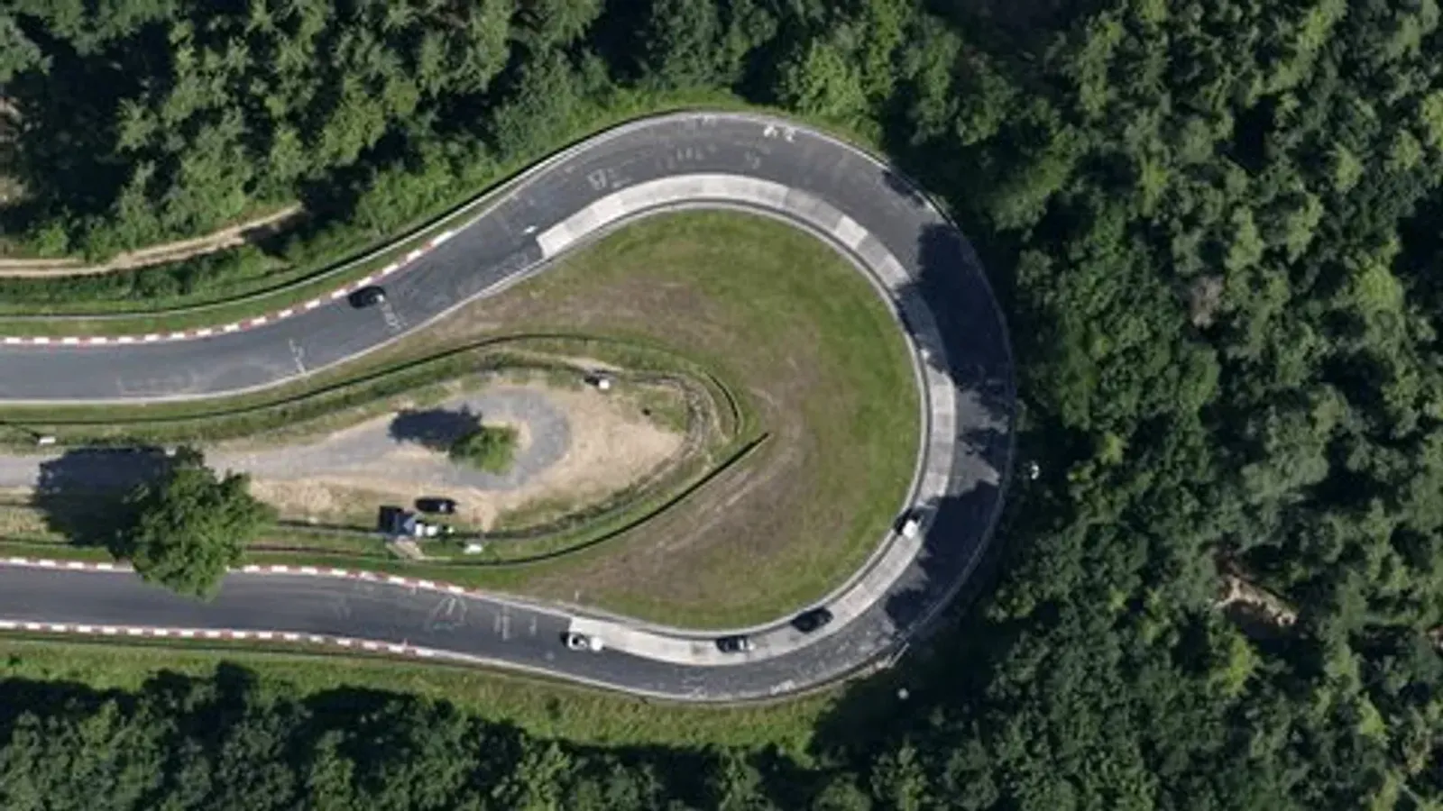 Vue aérienne par drone du Nürburgring Nordschleife serpentant à travers les collines boisées allemandes, avec des couleurs naturelles et contrastées soulignant le relief.